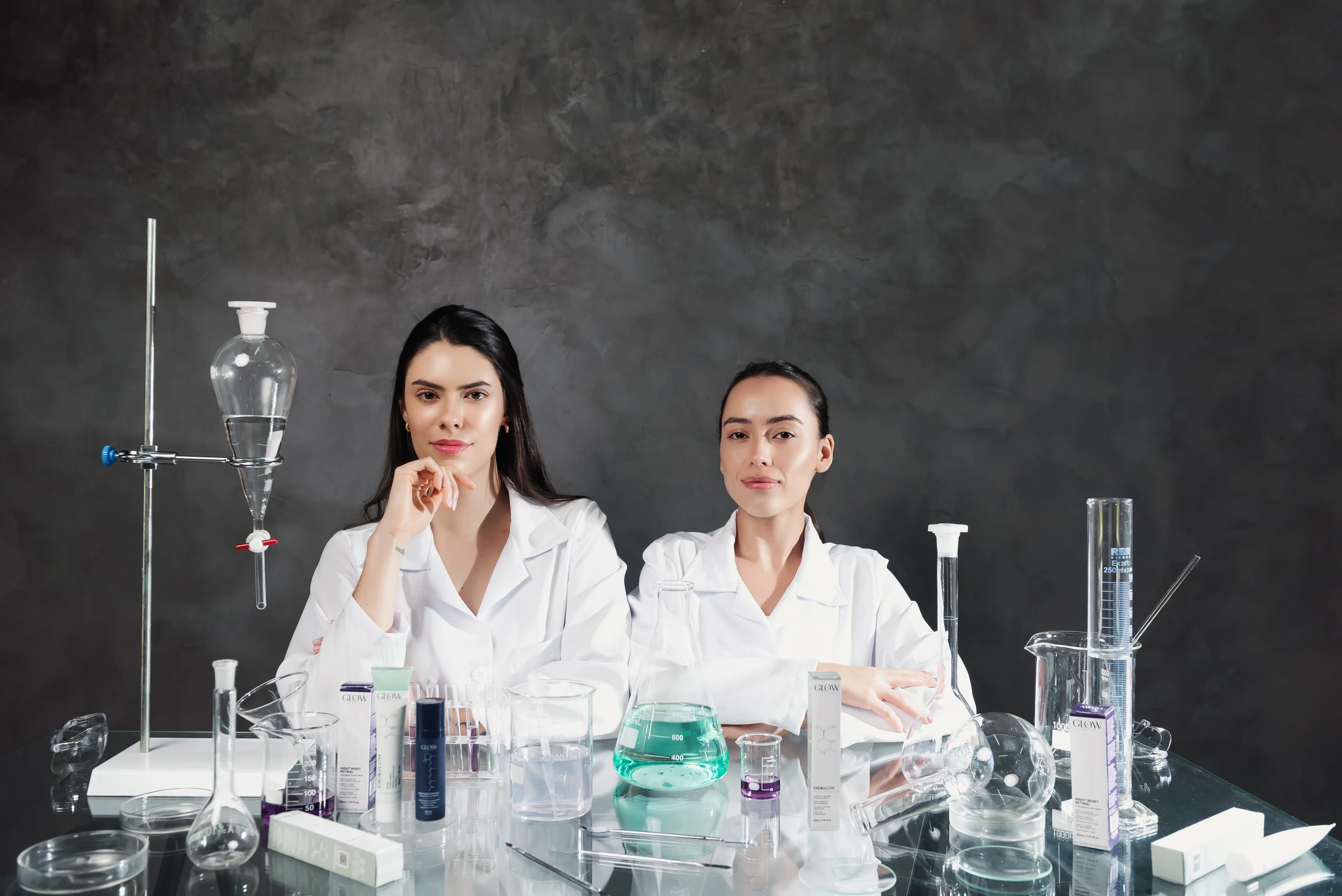 Duas modelos em bancada de laboratório com os produtos CicaGlow e Night Reset Retinal
